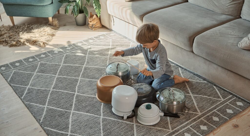 Child drummer having fun drum playing on kitchen pans at home