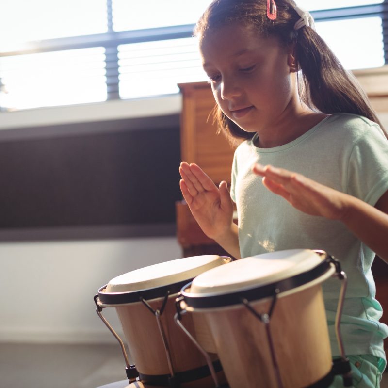 Girl playing bongo drums in classroom